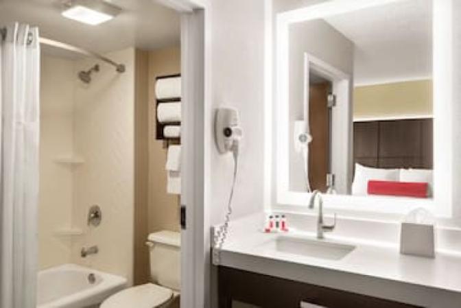 Bathroom inside a suite at the Ramada Suites Orlando International Airport Hotel, featuring a large back lit mirror.