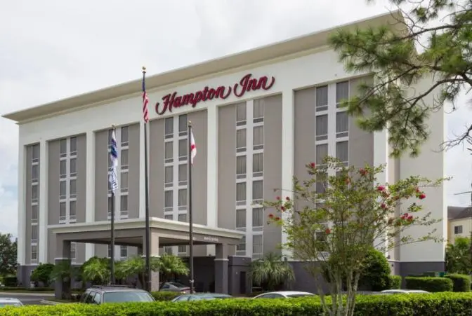 Exterior view of Hampton Inn Orlando International Airport Hotel with American and state flags at the entrance.