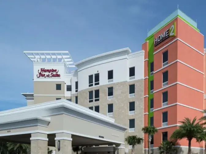 Entrance of Hampton Inn & Suites, showcasing modern architecture and landscaping.