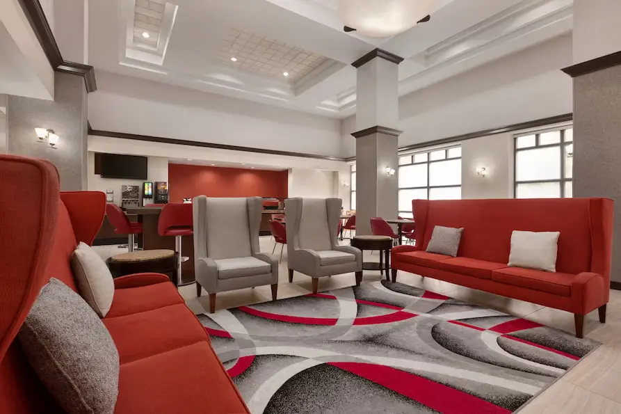 Ramada Suites lobby showcasing contemporary design and plush red seating.