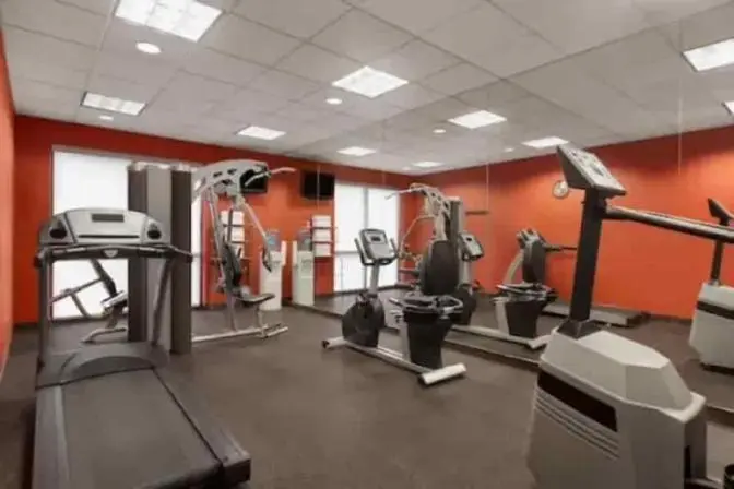 Ramada Suites fitness center featuring a variety of modern exercise equipment, including treadmills, stationary bikes, free weights, and large mirrors on the walls for an open and spacious feel.