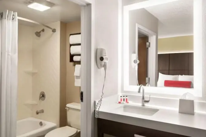 Bathroom inside a suite at the Ramada Suites Orlando International Airport Hotel, featuring a large back lit mirror.
