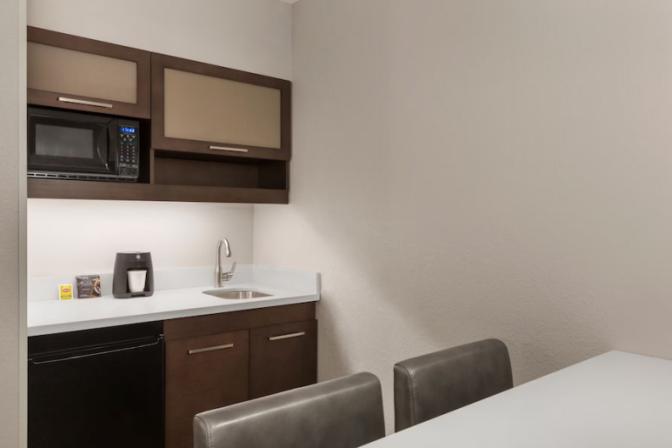 Kitchenette in Ramada Suites queen room featuring a mini refrigerator, microwave, sink and coffee maker.