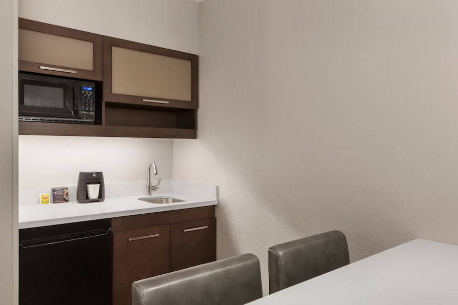 Kitchenette in Ramada Suites queen room featuring a mini refrigerator, microwave, sink and coffee maker.