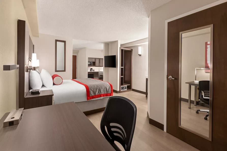 Modern king room at Ramada Suites featuring a comfortable king sized bed a kitchenette and a desk.