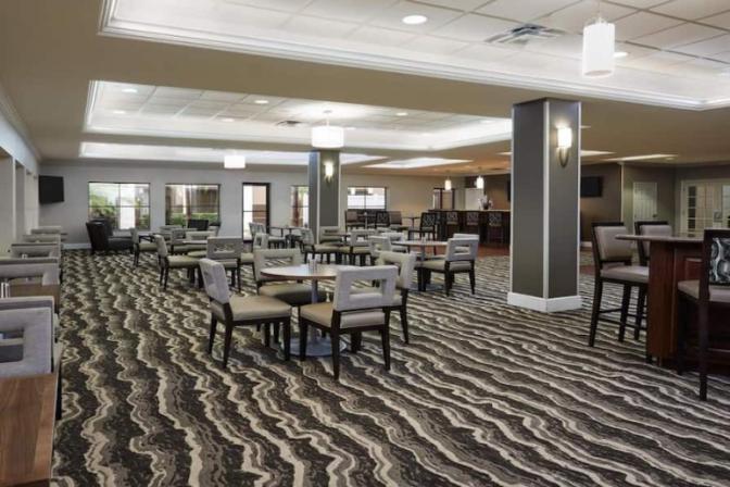 Spacious dining room in Staybridge Suites International Airport Hotel featuring a variety of seating options and contemporary design elements.