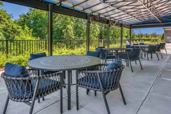 Spacious outdoor covered patio with fans, large round tables and comfortable seating.
