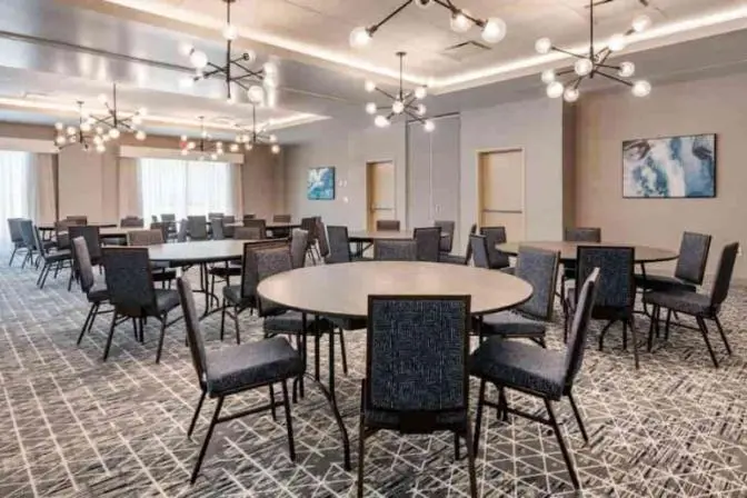 Cambria Orlando International Airport conference room setup with tables and chairs featuring stylish geometric ceiling light fixtures.