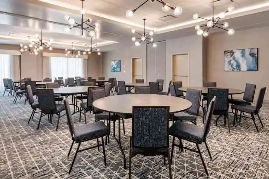 Cambria Orlando International Airport conference room setup with tables and chairs featuring stylish geometric ceiling light fixtures.