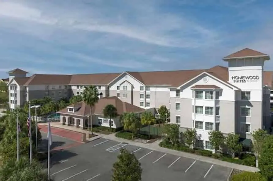 Homewood Suites by Hilton near Orlando Airport, featuring a welcoming exterior with warm afternoon lighting and a spacious parking area.