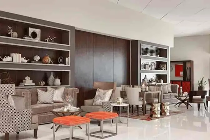 Renaissance Orlando Airport Hotel lobby lounge featuring plush seating, modern armchairs, decorative built-in shelving with books and art objects, and a warm neutral color palette with metallic accents.