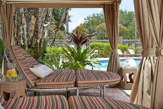 Private cabana area at Renaissance Orlando Airport Hotel with striped cushioned lounge chairs, tropical plants, citrus-infused water pitchers, and pool views surrounded by lush landscaping.