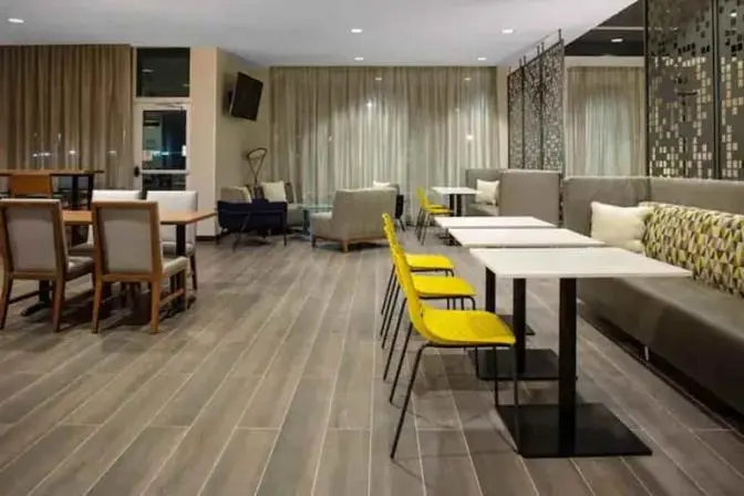 Sitting area in the lobby of the TownePlace Suites near Orlando Airport, featuring a booth and tables with bright yellow chairs.