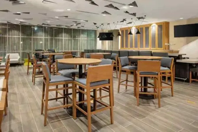High top bar chairs at round tables scattered throughout the room with paper airplane decor flying around the ceiling.