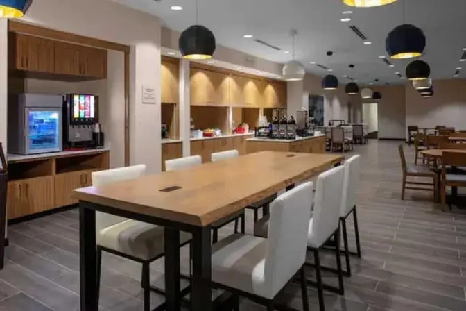 Large rectangular dining table near the self serve buffet style dining area in the TownePlace Suites near Orlando Airport.