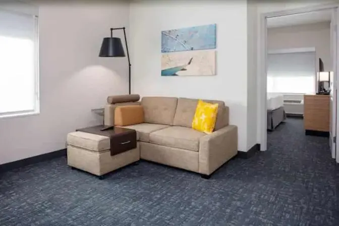 A couch in a room that has a king bed at the TownePlace Suites near Orlando Airport.