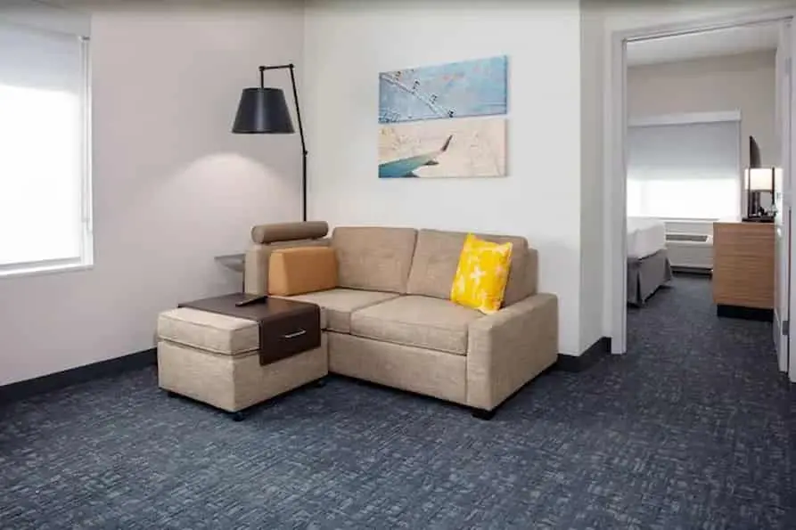 A couch in a room that has a king bed at the TownePlace Suites near Orlando Airport.