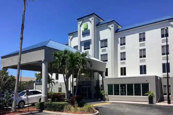 Hotel exterior of Holiday Inn Express Cocoa Beach, showing multi-story structure, main entrance canopy, and accessible parking area.