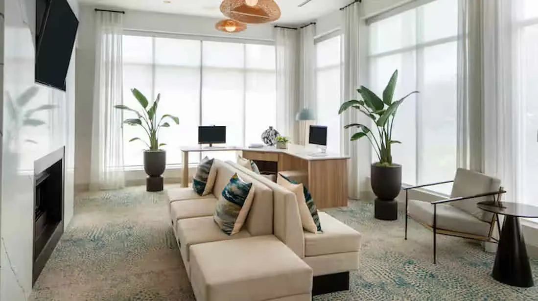 Business center at Hilton Garden Inn Orlando Airport featuring modern workstations with desktop computers, ergonomic chairs, and contemporary decor in a well-lit, professional setting.