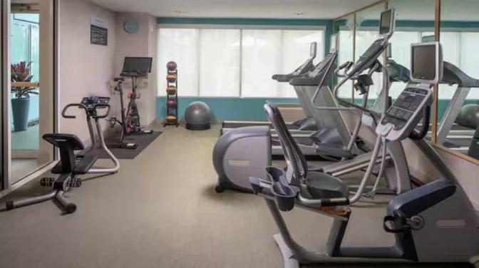 Fitness center with various exercise equipment including treadmills, stationary bikes, and weight benches.