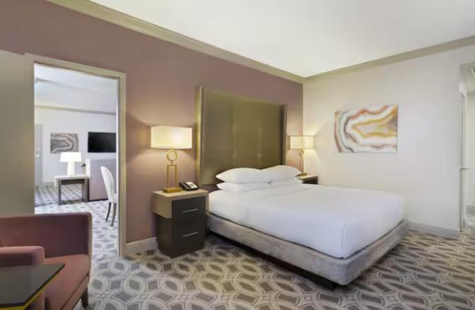 King guest room at DoubleTree by Hilton Hotel Orlando East-UCF Area featuring a modern design with a plush king bed, elegant lighting, and a separate sitting area with a flat-screen TV for added comfort.