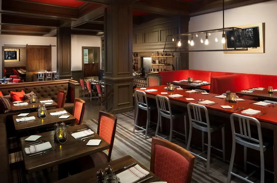 Cozy restaurant at Marriott Lakeside with a mix of red booths, tufted benches, and dark wood furnishings.