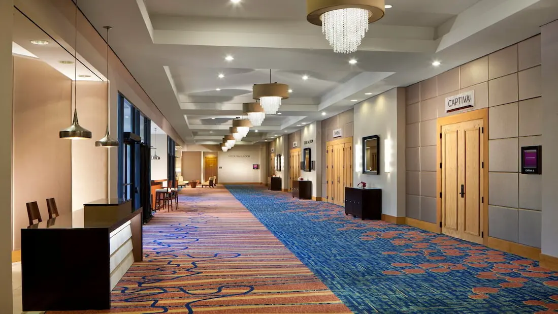 Spacious conference center hallway with modern lighting and colorful carpeting.