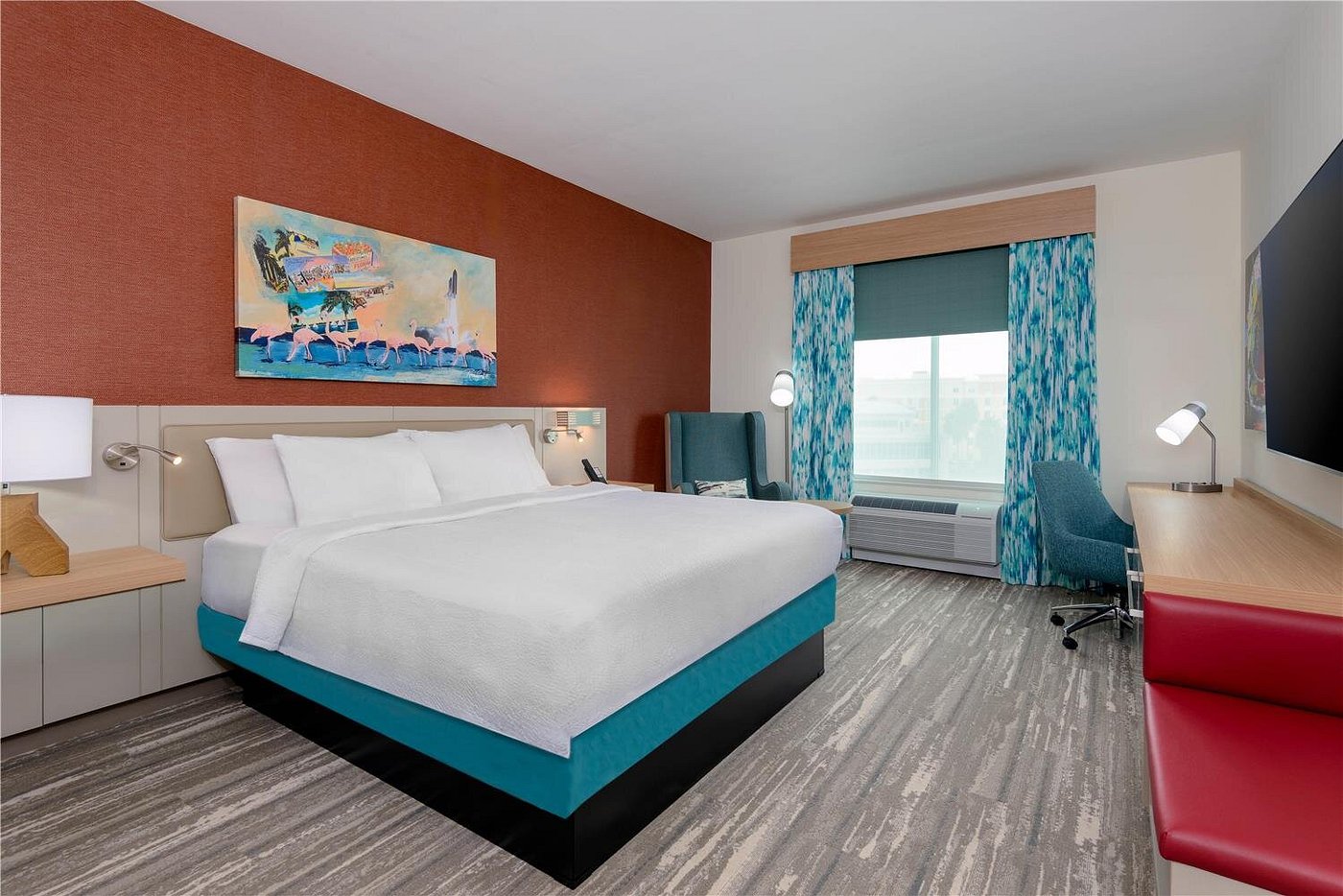 Guest room with king bed, workspace, and colorful coastal decor at Hilton Garden Inn Cape Canaveral near Cocoa Beach.
