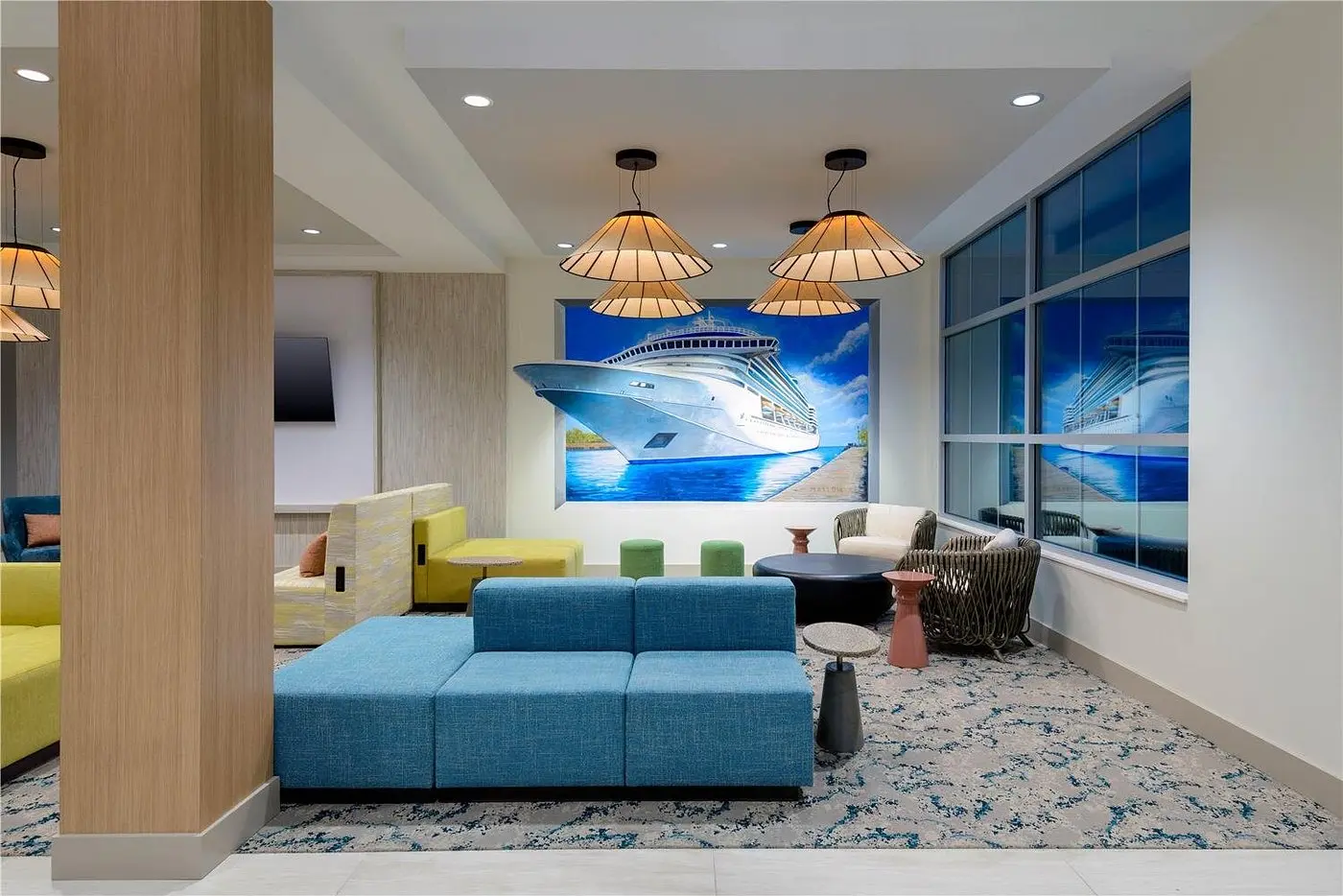 Hotel lobby lounge with modern seating and cruise ship mural at Hilton Garden Inn Cape Canaveral near Cocoa Beach.