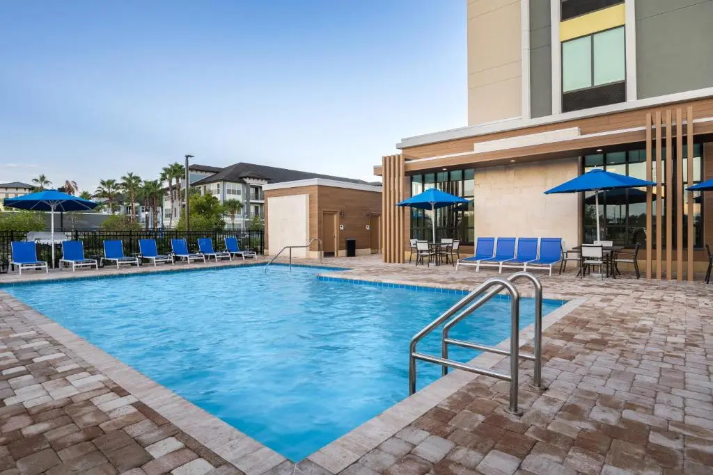 Outdoor pool area with lounge chairs and blue umbrellas at Hilton Garden Inn Cape Canaveral near Cocoa Beach.