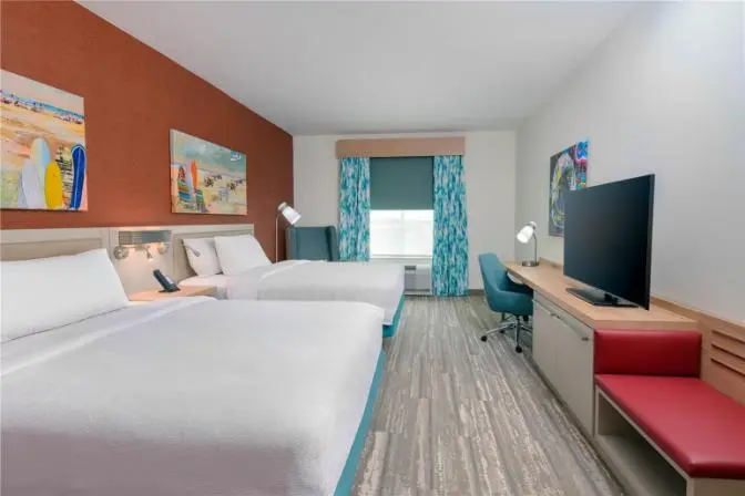 Double queen guest room with modern decor, workspace, and coastal artwork at Hilton Garden Inn Cape Canaveral near Cocoa Beach.