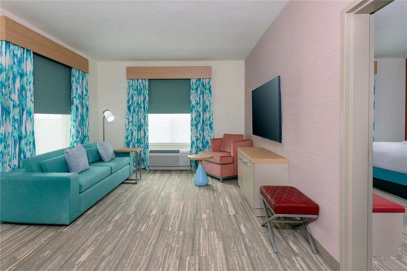 Spacious suite living area with sofa, lounge chair, and large TV at Hilton Garden Inn Cape Canaveral near Cocoa Beach.