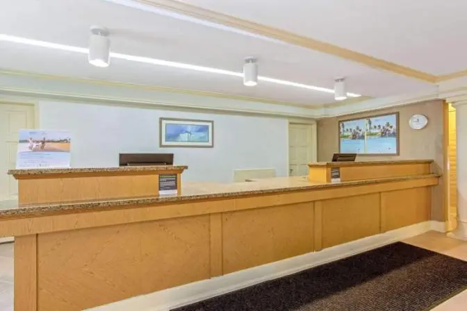 Hotel check-in desk and front desk area at La Quinta Inn by Wyndham Orlando Airport West.