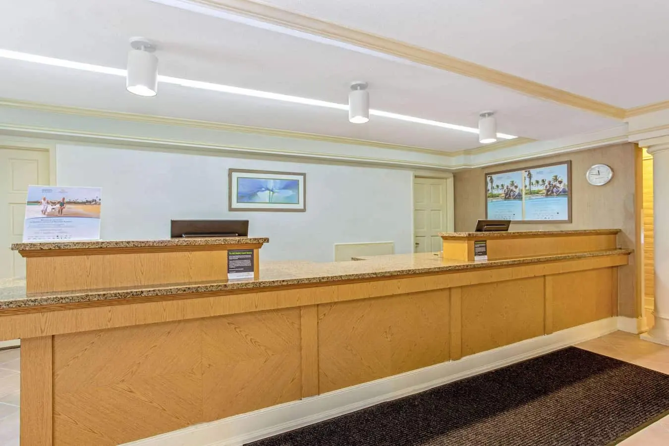 Hotel check-in desk and front desk area at La Quinta Inn by Wyndham Orlando Airport West.