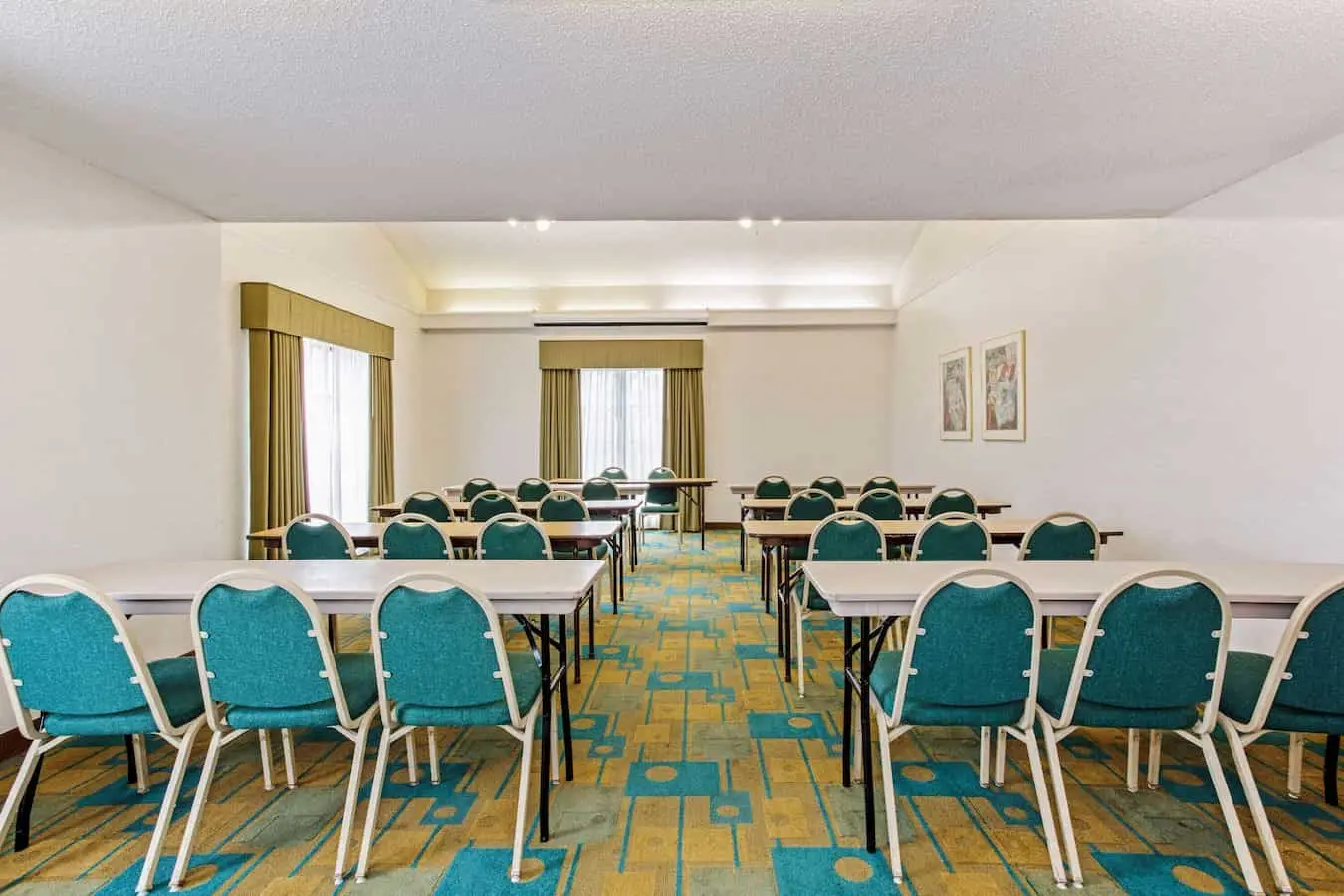 Meeting room with tables and chairs set up for events at La Quinta Inn by Wyndham Orlando Airport West.
