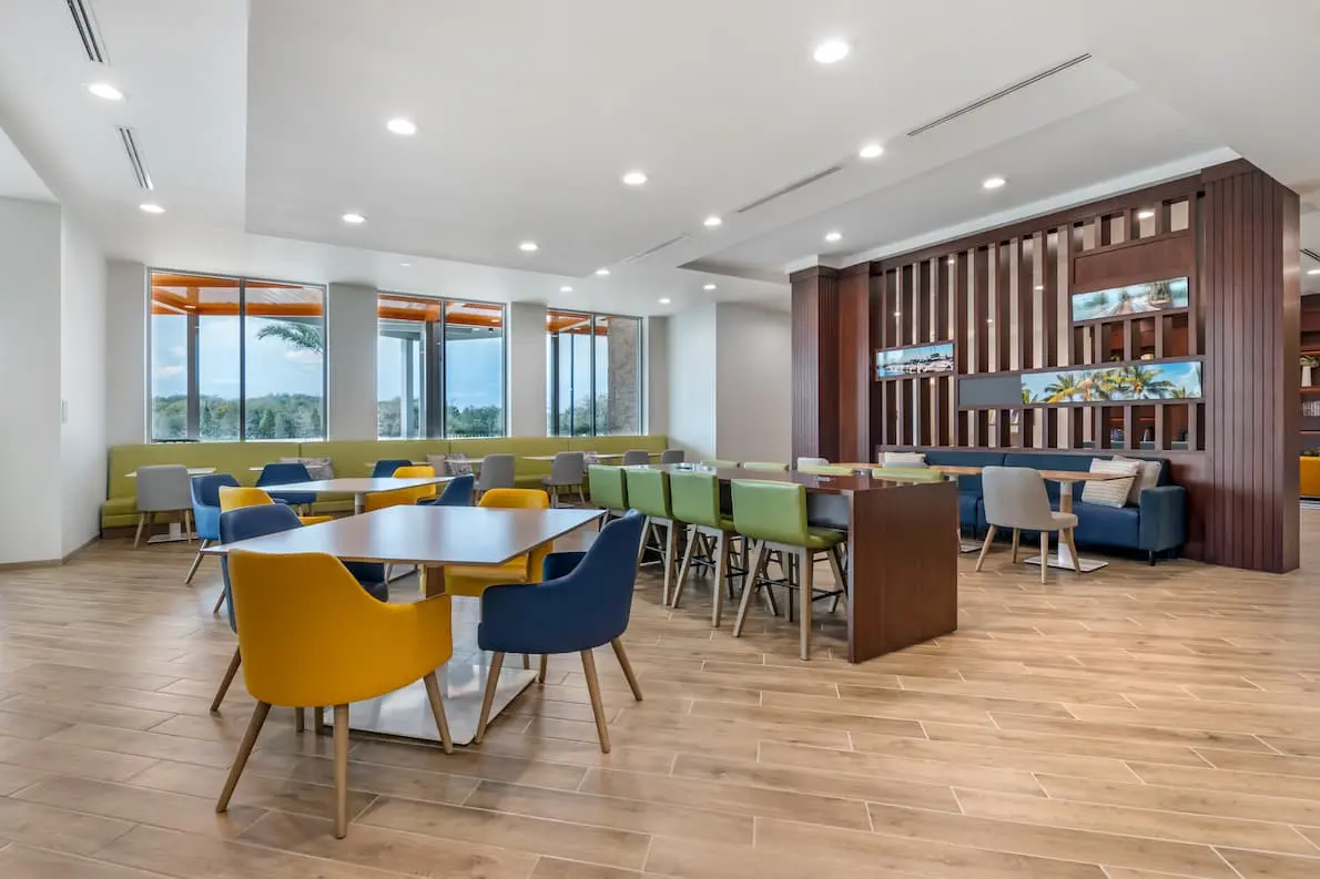 Comfort Inn & Suites dining area with tables, chairs, and sofas, featuring a window view.