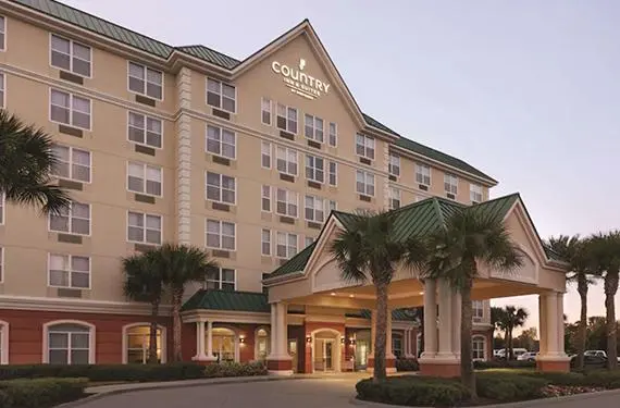 Country Inn & Suites near Orlando Airport, featuring a grand entrance with palm trees and warm evening lighting.